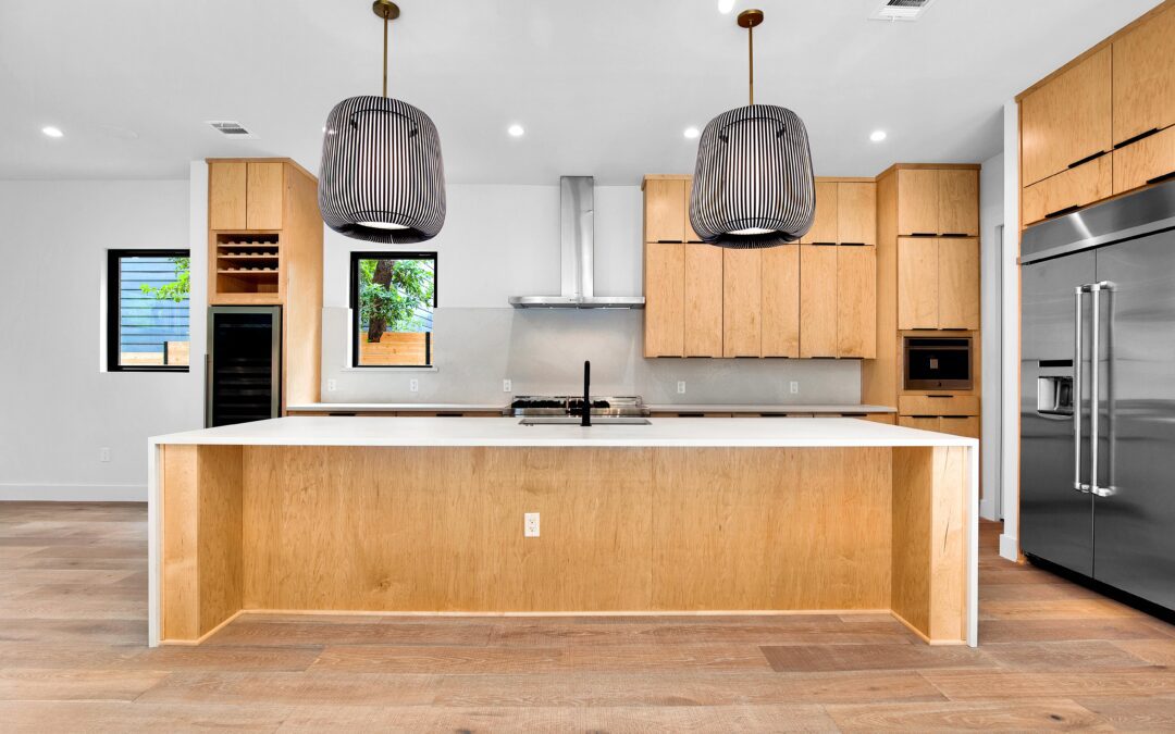 Modern kitchen interior with wooden cabinets, stainless steel appliances, and an island with pendant lights.